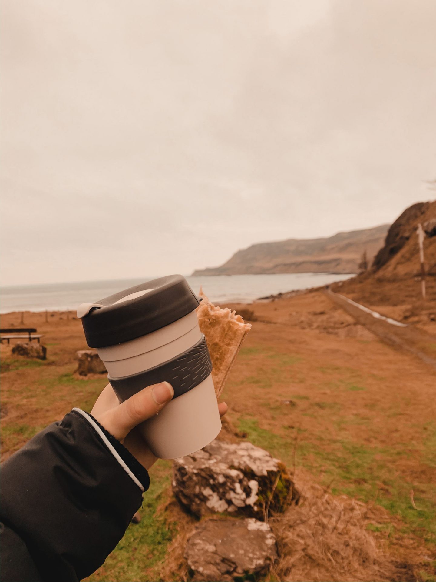 Travel Diaries: a week on the Isle of Mull at Hogmanay - keep cup and vegan sausage roll with the sea behind.