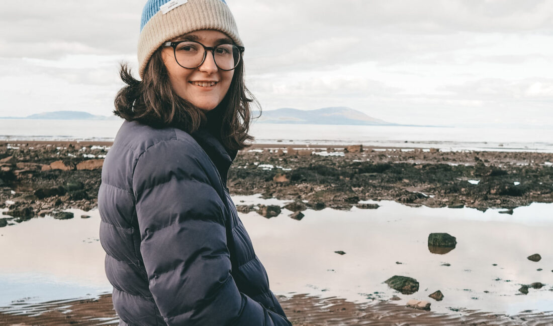 Katie smiling to camera sith the beach behind - the perfect wellbeing day out