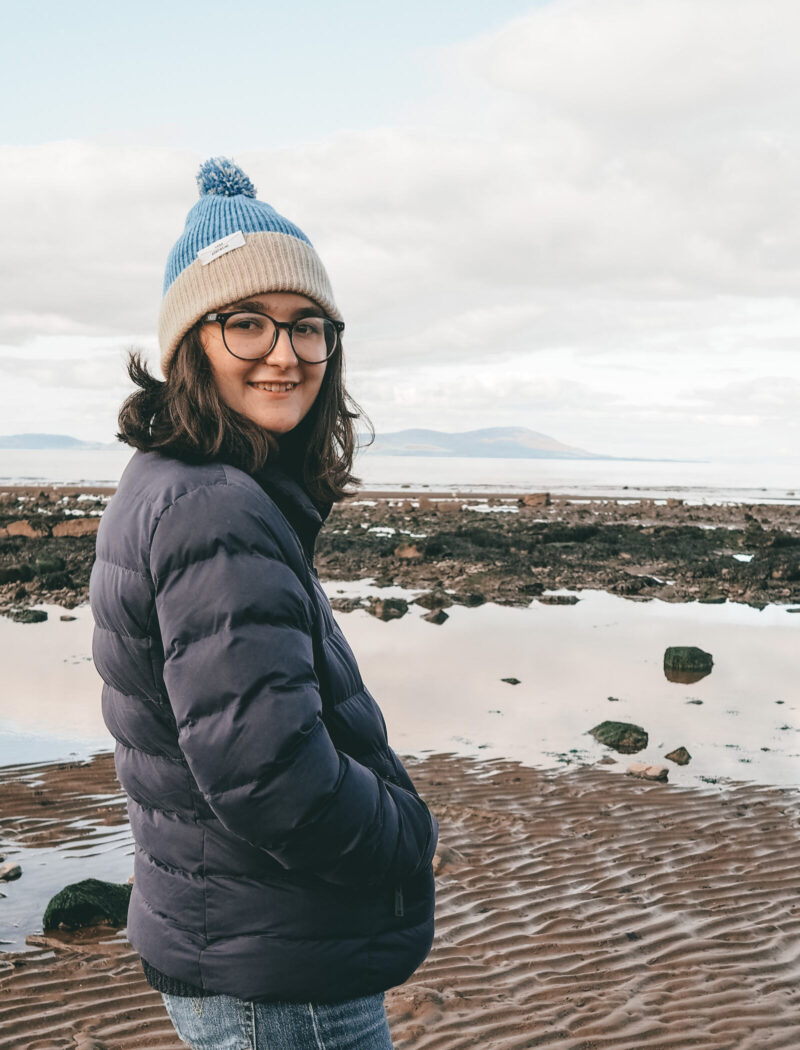 Katie smiling to camera sith the beach behind - the perfect wellbeing day out