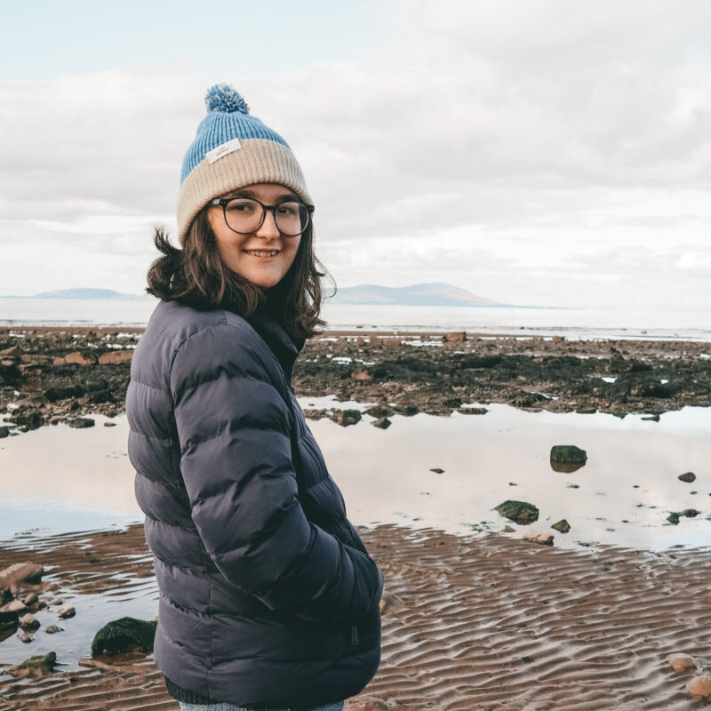 Katie smiling to camera sith the beach behind - the perfect wellbeing day out